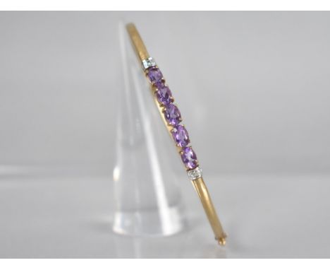 A 9ct Gold Gem Set Bangle, Five Oval Cut Amethysts, Each Measuring 6.3mm by 4.2mm Set in Four Claws and with White Metal Shou