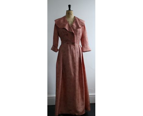 A vintage 1940s housecoat in a deep, dusky pink, satin rayon print. Features original buttons, 3/4 cuffed sleeves and a large