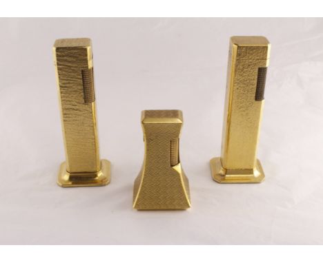 Two 1970's Dunhill Tallboy table lighters & another engine turned 'waisted' DUNHILL table lighter, all gold plated finish