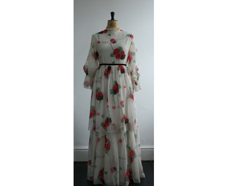 A 1970s flower print tiered maxi dress by Angela Gore, London. Features a high neck, velvet trim around waist and frilled sle