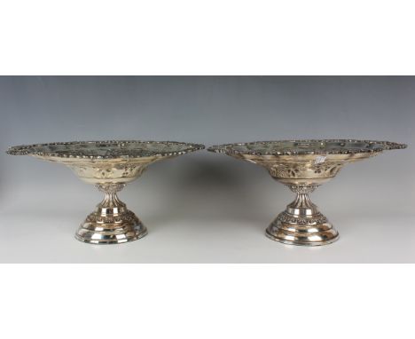 A pair of 20th century plated table centre tazzas, each bowl decorated in relief with fruit and leaves within a cast scroll r