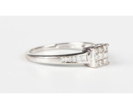 An 18ct white gold and diamond nine stone cluster ring, mounted with princess cut diamonds between baguette cut diamond set s