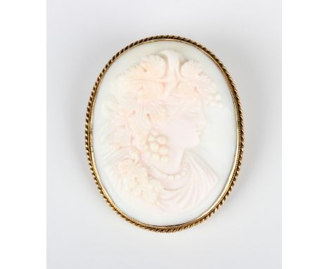 A gold mounted oval pink shell cameo brooch, circa 1900, carved as a portrait of a bacchante within a wirework border, unmark