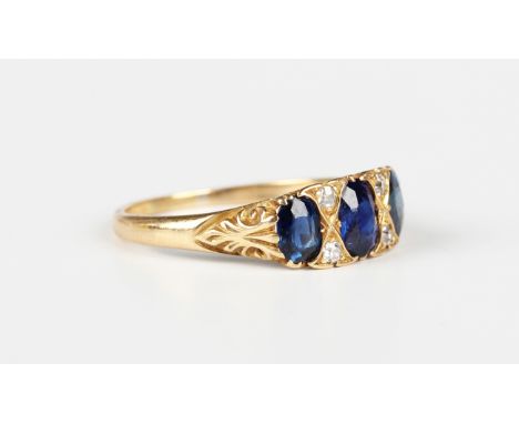 An Edwardian gold, sapphire and diamond ring, mounted with a graduated row of three oval cut sapphires alternating with two p