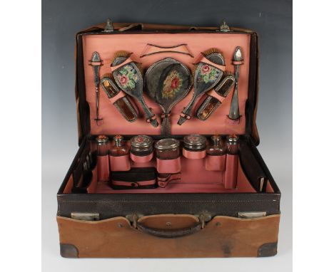 A George V leather travelling vanity case, the interior fitted with silver mounted dressing table items, comprising seven cut