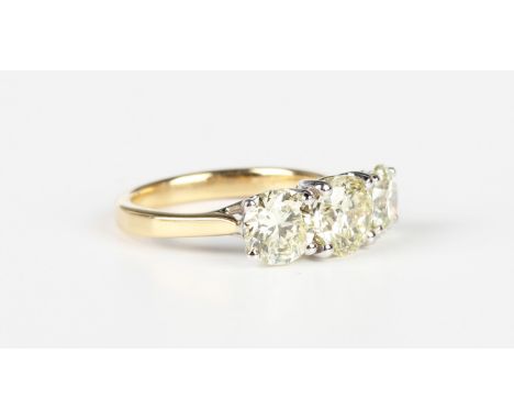 An 18ct two colour gold and diamond three stone ring, claw set with a graduated row of circular cut diamonds, weight 4.6g, to