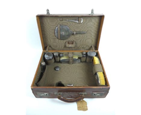 An early 20th century travelling dressing case with silver backed and mounted accoutrements, including pair of hairbrushes, h