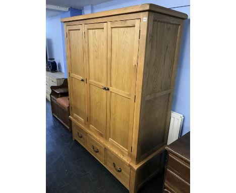 A light oak three door wardrobe, with three drawers below, 110cm x 190cm x 60cm