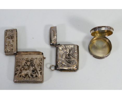 A Chinese silver plated vesta case with dragon decoration, white metal pill box with embossed floral decoration and one furth