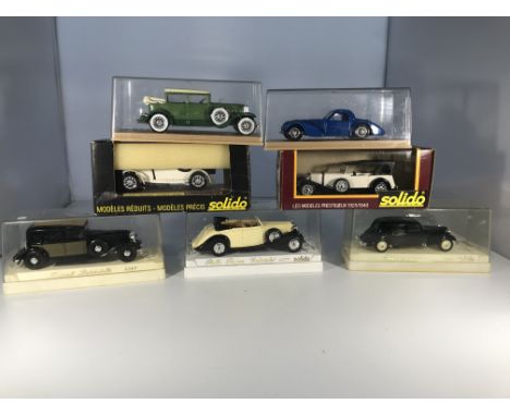 Seven Solido model cars in cases. A Cadillac 452 A, a Bugatti Atalante, a Mercedes SSKL, a Mercedes SS, a Renault Reinastella