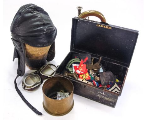 A group of miscellaneous militaria, including shoulder and cap badges, a leather flying helmet and goggles and a copper and b