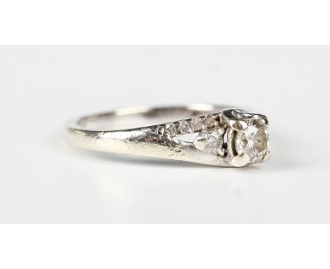 A 9ct white gold and diamond ring, claw set with the principal circular cut diamond between two smaller circular cut diamonds