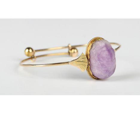 A gold and amethyst bangle, circa 1920, carved as a scarab beetle, the shoulders decorated in the classical Egyptian taste, u