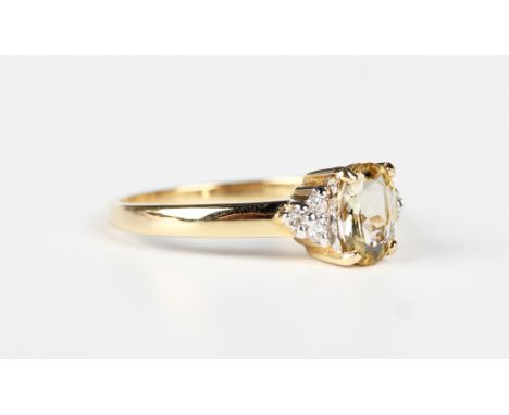 An 18ct gold ring, claw set with an oval cut yellow gem between circular cut diamond set three stone shoulders, detailed '750