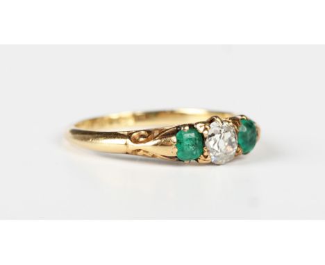 An 18ct gold, diamond and emerald three stone ring, circa 1910, mounted with a cushion cut diamond between two emeralds, the 