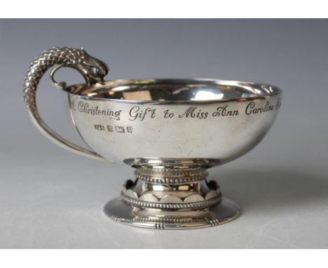 A George V silver circular cup with dragon handle, raised on a beaded and scalloped circular foot, the bowl rim with presenta