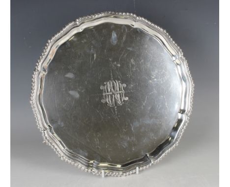 A George V silver circular salver, monogram engraved with a gadrooned rim, on claw and ball feet, Sheffield 1912 by Fordham &