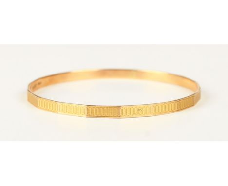 A 9ct gold faceted circular bangle with engine turned decoration, Birmingham 1932, weight 15.6g, inside diameter 7.2cm.Buyer’