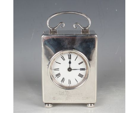 An Edwardian silver cased carriage timepiece with scroll carrying handle above a circular white enamel dial with Roman numera
