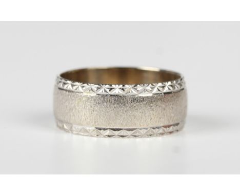 A 9ct white gold wide band wedding ring with textured decoration between facet cut sides, London 1978, weight 5.7g, ring size
