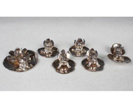 A set of four Elizabeth II silver novelty menu holders, each in the form of a frog seated on a lily pad before three lily pet