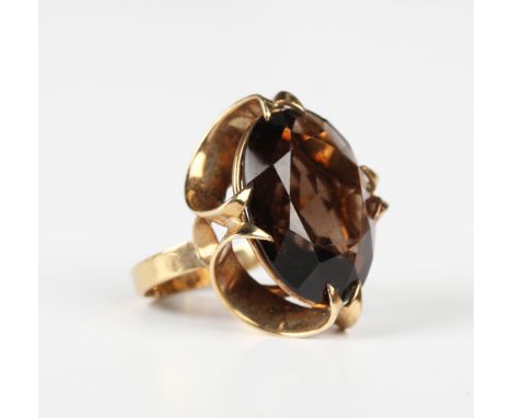 A 9ct gold and smoky quartz solitaire ring, claw set with the oval cut smoky quartz in a raised openwork loop design, London 