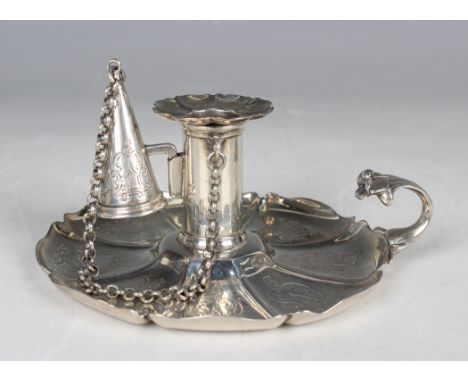 A Victorian silver chamberstick of circular lobed form, engraved with scrolls, flanked by a foliate scroll handle, with detac