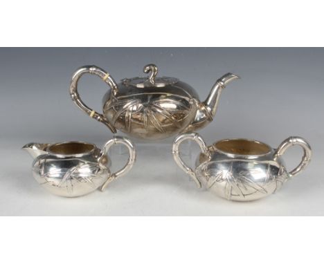 An early 20th century Chinese silver three-piece tea set, each piece of squat circular form, decorated in relief with stems o