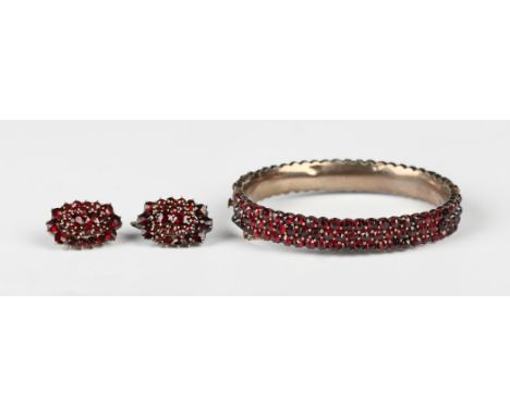A Bohemian garnet oval hinged bangle, circa 1900, mounted with three rows of Bohemian garnets, on a snap clasp, inside width 