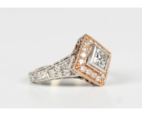 A two colour gold and diamond ring, mounted with the principal princess cut diamond in a square shaped setting within a surro