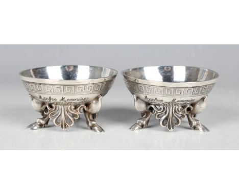 A pair of Victorian silver circular salts, each engraved with a stylized Greek key border above a pierced apron, on three hoo