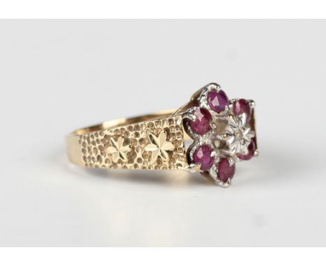 A 9ct gold, ruby and diamond cluster ring in a flowerhead shaped design with foliate textured sides, London 1984, weight 4.1g