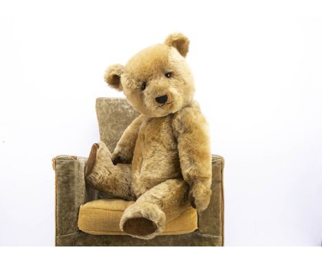 A post-war Chiltern Hugmee teddy bear,  with blonde mohair, orange and black glass eyes, slight pronounced muzzle, black stit