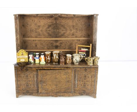 A lithographed tinplate doll's dresser,  probably a produce tin of maple wood and opening cupboard door --13in. (33cm.) wide;