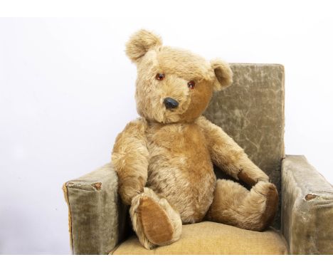 A post-war Chiltern Hugmee teddy bear,  with blonde mohair, orange and black glass eyes, black plastic nose, black stitched m