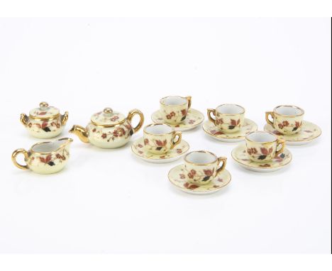 A late 19th century fashion doll’s porcelain tea set, pale yellow ground painted with gold, black and brown flowers and sprig