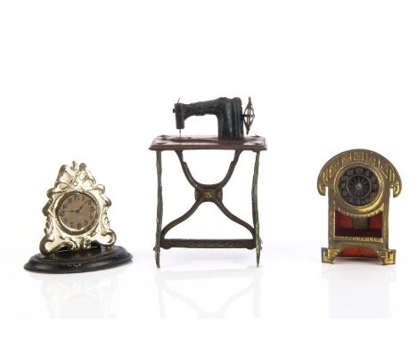 A Penny Toy dolls’ house sewing machine, spirit painted tinplate —3¼in. (8cm.) high; and two Penny Toy mantel clocks