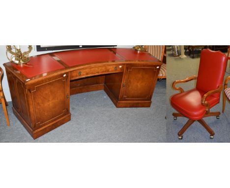 A modern red leather inset bur yew kneehole desk, the moulded curved top over a central drawer flanked by a pair of cupboards