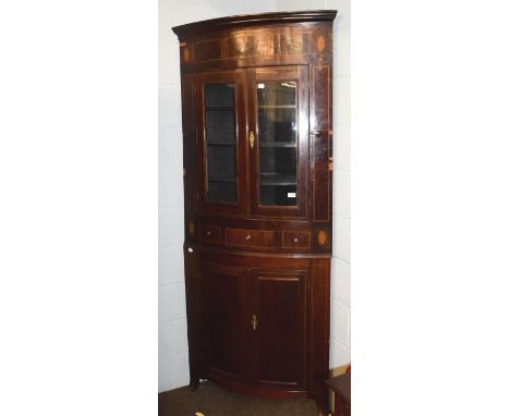 A 19th century inlaid mahogany bow-front standing corner cupboard with glazed top section and raised on splayed bracket feet,