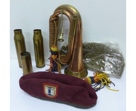 A WWI cloth cap with Cornwall Regimental badge and a maroon beret, plus three shell cases and a bugle