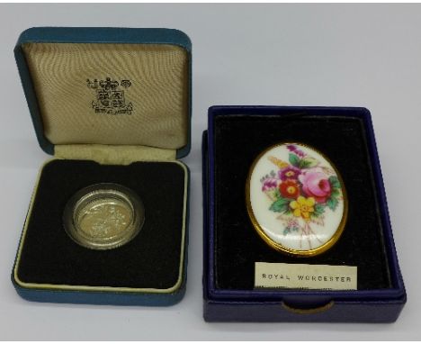 A silver proof one pound coin and a Royal Worcester brooch