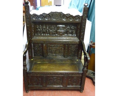 A good 17th Century style carved oak box seat hall bench, profusely carved patterns and mottos with deep carved inset back pa