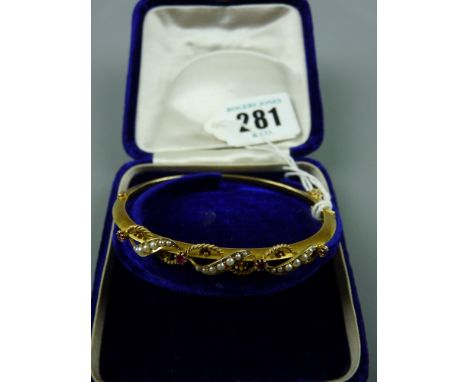 A fifteen carat gold narrow bangle decorated with three scrolled bands of seed pearls and twisted decoration supporting four 