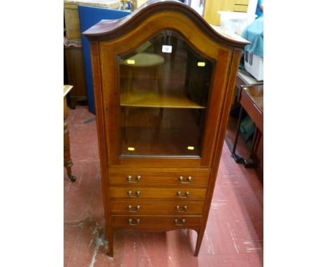 An Edwardian inlaid mahogany dome topped cabinet with bevelled glass door and interior shelf over four shallow drawers and sh