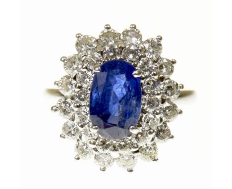 A sapphire and diamond cluster ringThe oval shape sapphire within a brilliant cut diamond tiered surround, estimated total di