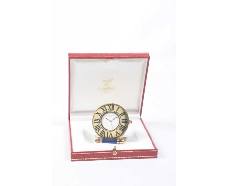 A Must de Cartier folding travel clockThe circular dial within a gilt metal case with blue enamel Roman numeral hour markers 