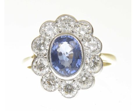 A sapphire and diamond cluster ringThe oval shape sapphire within a brilliant cut diamond scalloped surround, stamped 18ct, e