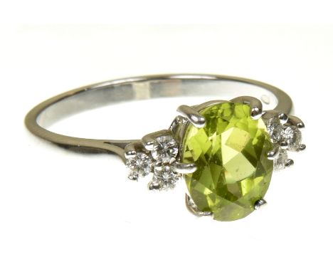 An 18ct  gold peridot and diamond dress ringThe oval shape peridot with brilliant cut diamond trefoil sides estimated total d