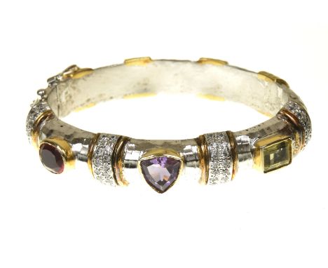 A diamond and gem set bangleThe vari shape amethyst, yellow quartz and red paste line atop the bi-colour metal planished bang