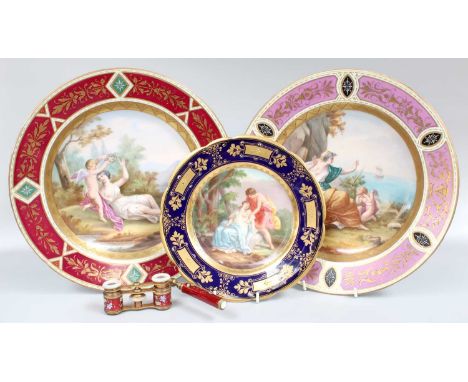 A Pair of Vienna Style Porcelain Chargers, with coloured panelled grounds framing central painted scenes of Cupid and Aphrodi